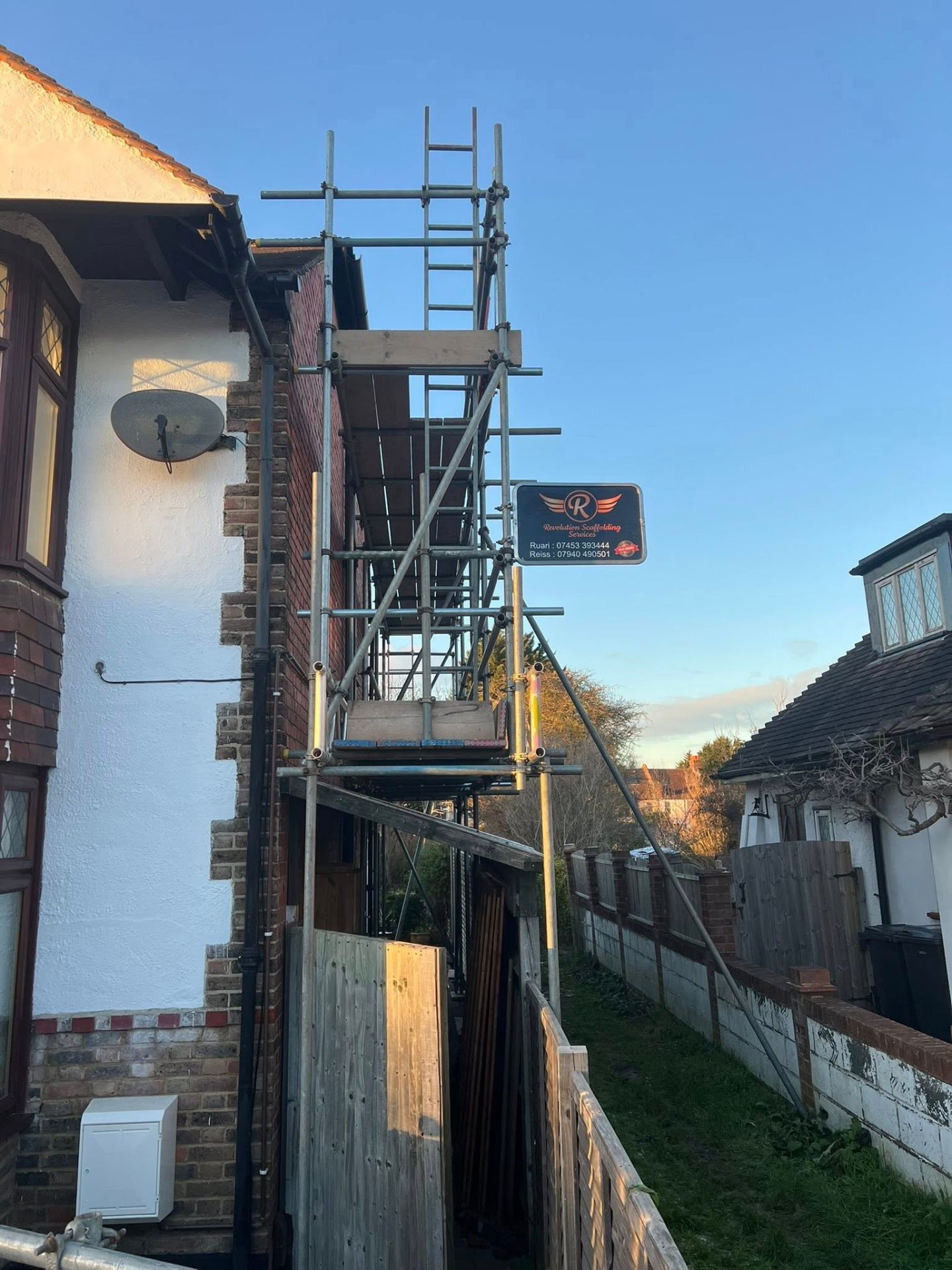 Side-return access scaffold with branded board on a Beckenham home